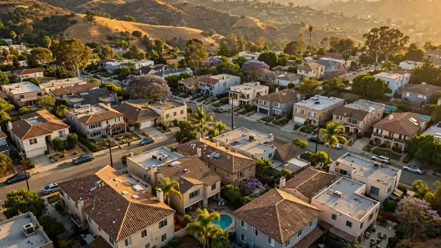 Aerial view over Los Angeles residential rooftops with hills behind at golden hour